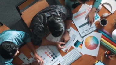 Tasarımcı fikirleri yazarken proje yöneticisinin yukarıdan aşağıya bakan görüntüsü. Akıllı iş adamları logo tasarımı fikrini açıklarken tasarımcılar palete bakarken temayı seçiyorlar. Sempozyum.