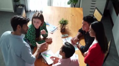 Mutlu yaratıcı takımın zihin haritası çizerken el ele tutuşması. Çeşitli insanlar birlikte çalışarak pazarlama fikri üzerinde çalışıyor ve yapışkan notlar kullanarak planlarını paylaşıyorlar. Cemaat