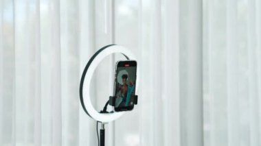 Arkadan bakıldığında kadın nüfuzlu kişi canlı yayın vlog görüntülerini çeker. Önemli sosyal medya ya da blogu gizler. Stüdyo ışıklandırmalı bir kız çevrimiçi pazarlama oturumu yayını için.