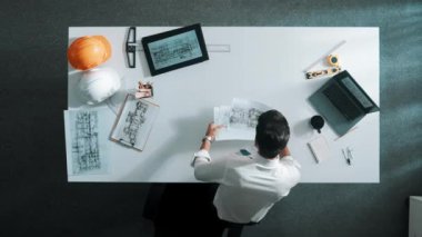 Proje planını kontrol ederken ve seçerken mimar mühendisin bina planlarını masaya yerleştirdiği tepeden aşağı hava görüntüsü. İç mimar toplantı masasından mimari plan seçti. Hizalama.