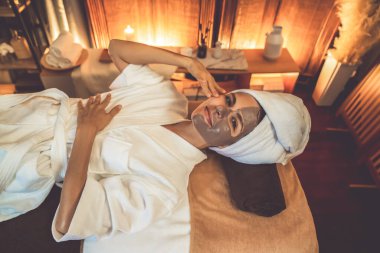 Kaplıca salonunun sakin atmosferi, üst düzey kadın müşteri sıcak mum ışığında kömür kömürü yüz kremi masajıyla kendini yenilemeye çalışıyor. Yüz bakımı ve güzellik konsepti. Sessiz.