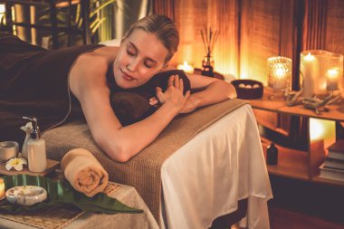 Beyaz kadın müşteri stres önleyici spa masajının keyfini çıkarıyor ve lüks otel ya da otelde sıcak mum ışığında güzellik teniyle eğleniyor. Sessiz.