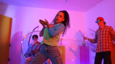 Çekici mutlu dansçı kameraya bakarken zeki kadın neon ışıkla kafiyeli hareket ediyor. Profesyonel İspanyol şarkıcı çeşitli arkadaşlarıyla renkli kıyafetler giyerken break dans yapıyor. Mutluluk.