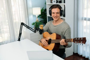Akıllı şarkıcı görünümlü kamerada sunucu kanalı, şarkı söylerken gitar çalmak, sosyal medya kanalında yayın yapmak, modern stüdyo kaydında video kaydedici olarak kulaklık takmak. Bireysel.