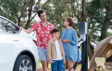 Outdoor adventure and family vacation camping in nature travel by eco friendly car for sustainable future. Lovely family recharge EV car with EV charging station in campsite. Perpetual clipart