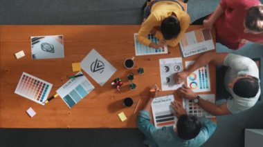 Proje yöneticisi renk paletleri seçerken tasarımcının tablete baktığı yukarıdan aşağıya hava görüntüsü. Profesyonel grafik tasarımının en üst görüntüsü ve logoya bakın. Yetenekli ekip grafikleri seçiyor. Sempozyum.