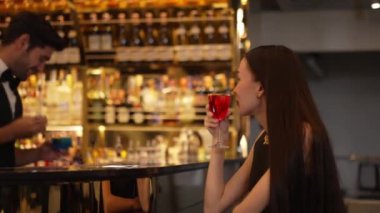 Barmen lüks tezgah barında güzel misafirler için çiçeklerle süslenmiş karışık votka kokteyli servis ediyor. Mükemmel canlı renk sunumu. Atmosfer gece kulübünü ön plana çıkarıyor. Vinosity.