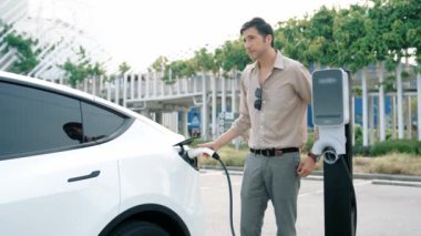 Yavaş çekim adamı, EV şarj aletini şehrin alışveriş merkezinin otoparkındaki şarj istasyonundan şarj etmek için kullandı. Sürdürülebilir şehirde EV aracı tarafından şarj edilebilir enerji olarak kullanıldı.