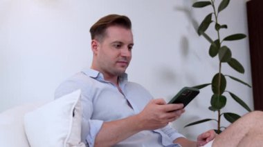 Orta yaşlı bir adam oturma odasındaki koltukta oturur telefon arama verilerini kullanır çocukları iyi bir yetişkin baba ya da eğlence olarak yetiştirir. İşadamı teknolojiyi kolaylık için kullanır. Uyumsuzluk.