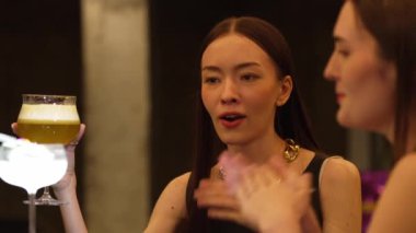 Güzel bir kadın, elinde bir bardak hindistan cevizli, köpüksüz içecek olan bir arkadaşıyla karışık çarkıfelek meyveli kokteyli hazırlıyor. Gece kulübü tezgahı partisinde canlı bir sohbete girişiyor. Vinosity.