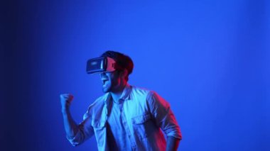 Oyun sahnesini temizlemek ya da maçı kazanmak için VR gözlükleri ve günlük kıyafetleriyle kutlama yapan çekici bir oyuncu. Akıllı iş adamı başarılı projeyi ya da satışları artırmayı kutluyor. Teknoloji. Aygıt.