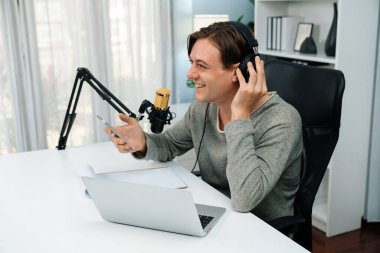 Sunucu kanalı, gülümseyen akıllı yayıncı kaydı, senaryosu ve akıllı telefonuyla sosyal medyada sohbet programı, kulaklık takarak modern ev stüdyosundaki video flamalarını kaydediyor. Bireysel.