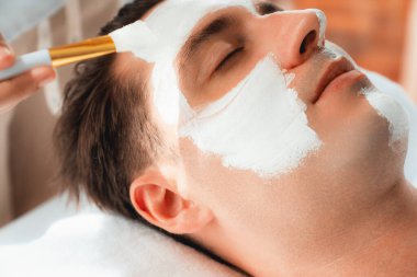 Kaplıca salonunun sakin atmosferi, insan müşterisi modern gün ışığında lüks yüz kremi masajıyla kendini yenileme zevkine kapılıyor. Yüz bakımı ve güzellik konsepti. Sessiz.