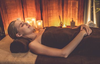 Beyaz kadın müşteri stres önleyici spa masajının keyfini çıkarıyor ve lüks otel ya da otelde sıcak mum ışığında güzellik teniyle eğleniyor. Sessiz.