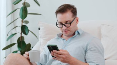 Orta yaşlı bir adam, iş için telefon arama verilerini kullanarak, çocukları iyi bir yetişkin ya da eğlence olsun diye odada kahve fincanıyla koltukta oturur. İşadamı teknolojiyi kolaylık için kullanır. Uyumsuzluk.