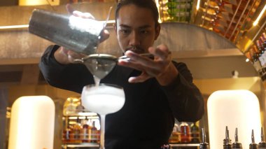Lüks tezgah hazırlamada süzgeç karışık votka kokteyli kullanan zeki Asyalı barmen ön taraftaki bardaki VIP konuğa özel içecek menüsü hazırlıyor. Gece hayatını gösteren özel bir içecek. Vinosity.