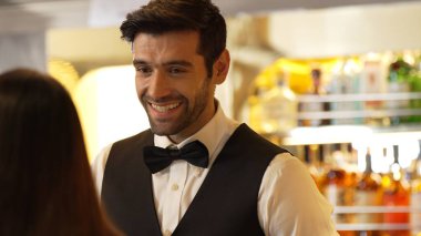 Gülümseyen zeki barmen, gece kulübünde VIP müşterilerle canlı sohbetler yapmak için güzel bir gece partisi atmosferine mükemmel bir servis sunuyor. Vinosity.