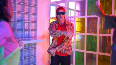 Kafkas dansçısı dans ederken çeşitli arkadaşları gece kulübünde neon ışıkta ayak seslerine bakıyor. Çoklu etnik kökenli hipsterin serbest stil müziğe geçişi ve mutlu bir adamın kameraya bakışıyla. Mutluluk.