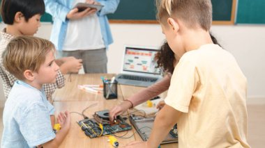 Öğretmenler tablet verileri analiz ederken sevimli enerjik çocuklar elektronik panoda çalışıyor. Çeşitli öğrenci grubu ana tahtayı tamir ediyor ve yapay zeka ve programlama sistemini öğreniyor. Pedagoji.