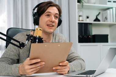 Akıllı yayıncının sunucu kanalı canlı sosyal medya yayını ile dinleyicilere senaryo okuyarak, kulaklık takarak modern ev stüdyosundaki video flamalarını kaydediyor. Bireysel.