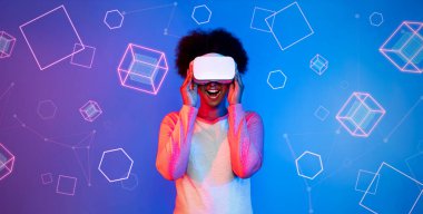 VR gözlüklü Afrikalı kız mavi ve pembe arka planda duruyor ve yüzen geometrik şekle bakıyor. Heyecanlı insan görsel gerçeklik dünyasına giriyor. Teknoloji yeniliği. Yaratıcılık.