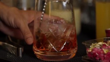 Yakın plan el yapımı barmen karışık alkollü likör şurubu karıştırıp buzla karıştırıyor. Barda eski moda kokteyl tatma kokteyli hazırlıyor ve gece hayatı karışımı sergiliyor. Vinosity.