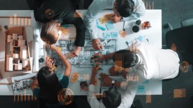 Profesyonel inşaat mühendisi ekibinin üst düzey görüşü ev modeline yapışkan notlar yazıp not tutarken iç mimar da finansal istatistik tablosunu tartışıyor. Hizalama.