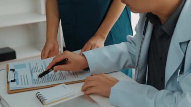 Hastane masasında birlikte çalışan ve tıbbi tedavi planlayan çeşitli profesyonel sağlık görevlileri. Takım çalışması başarılı hastalıklara ve hastalıklara yol açar. Ağır çekim. Katı.