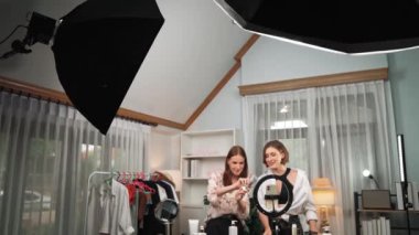 İki kadın nüfuzlu partner sosyal medya veya blog için canlı yayın yapan video klip inceleme derisi çekiyorlar. Kozmetik stüdyosu ışıklandırması olan genç bir kız pazarlama oturumu çevrimiçi yayın yapıyor.