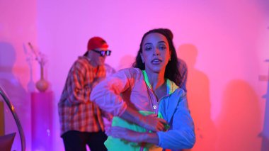 Çekici mutlu dansçı kameraya bakarken zeki kadın neon ışıkla kafiyeli hareket ediyor. Profesyonel İspanyol şarkıcı çeşitli arkadaşlarıyla renkli kıyafetler giyerken break dans yapıyor. Mutluluk.