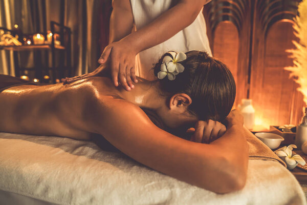 Caucasian woman customer enjoying relaxing anti-stress spa massage and pampering with beauty skin recreation leisure in warm candle lighting ambient salon spa at luxury resort or hotel. Quiescent