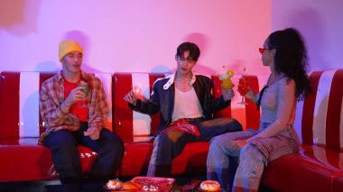 Takım çalışmalarını kutlamak için neon lambalı çok kültürlü bir arkadaş bardak tokuşturuyor. Renkli meyve suyu ve tokuşturarak şık modaya sahip profesyonel çeşitli insanlar. Mutluluk.