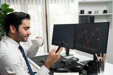 Elinde telefon dinamiğine odaklanan kahve fincanı tutan borsa yatırım ekranı veri analizini karşılaştırarak iç işlerinde yüksek kârlı finans teknolojisi pazarına yatırım yapıyor. Tahmin et..