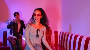 Enerjik İspanyol kız dans ediyor ve çok kültürlü arkadaşıyla müziğe geçiyor. Çeşitli insanlar serbest stil ve komik adımlar atarken aynı zamanda bayan dansçı performansını destekliyorlar. Mutluluk.