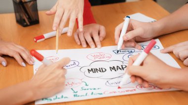 Yetenekli iş adamlarına yakın çekim yapmak beyin fırtınası yapmak, birlikte çalışmak, toplantı masasında zihin haritası ve renkli kalemler kullanarak pazarlama fikrini tartışmak. Eline odaklan. Tertemiz..