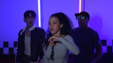 Gündelik gömlekli, gözlüklü, neon ışıkla dans eden farklı insanlar. Gece kulübünde dans ederken kameraya bakıp sokak dansı yapan çok kültürlü break dansçı. Mutluluk.