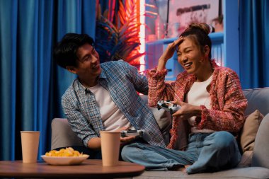 Oyun oynayan mutlu çiftin oturduğu kanepe joystickle oyun oynuyordu. Önden atıştırmalıklar ve kazanmak için gözlerini kapayan içkiler, evdeki modern neon ışıklı oturma odasında eğlenceli bir şekilde meydan okumaydı. İnfobahn.