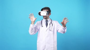 VR kulaklık ve laboratuvar önlüğü giyerken tıbbi verileri yönetmek için el ele tutuşan yetenekli bir tıp çalışanı. Profesyonel doktor mavi arka planda duruyor ve arttırılmış gerçekliği kullanıyor. Aygıt.