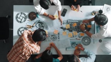 Üstten görünüşlü akıllı mühendis ekibi metal teçhizatlı, hesap makineli, yapışkan notlu türbin motor yapısı hakkında konuşuyor. Bir grup teknisyen toplantıda not alıyor. Hizalama.