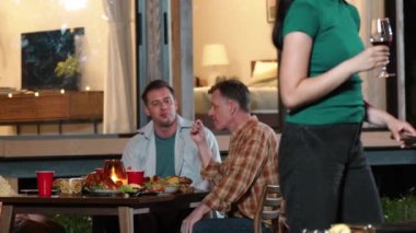 Anne ve büyükanne, aile üyeleri yıldönümü kutlamalarında yemek yerken ızgara yapıyor. Güzel akrabalarla vakit geçirmek için açık hava kamp aktiviteleri kuşaklar arası fark yaratır. Uyumsuzluk.