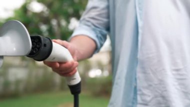 Modern çevre dostu adam EV şarj istasyonundan elektrikli aracı şarj ediyor. EV araba teknolojisi ev sakinleri için gelecekte çevresel sürdürülebilirlik için kullanılıyor. Titiz