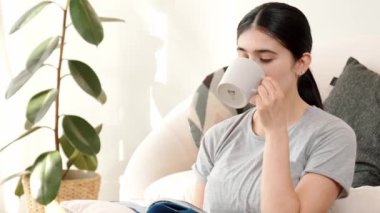 Elinde kahve fincanı olan bir kadın, ders kitabı okur, sosyal ve mesleki teknoloji bilgisini arttırır ya da akıllı bir anne olmak için çocuk yetiştirir. Hayat boyu öğrenme konsepti. Uyumsuzluk.