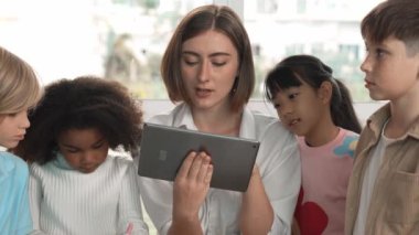Bir grup öğrenciye çevrimiçi ders verirken elinde tablet tutan akıllı öğretmen. Yetenekli eğitmen mühendislik derslerini anlatırken genç öğrenci oturuyor ve sunumu dinliyor. Etkinlik.