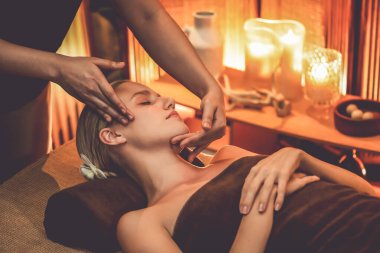 Beyaz kadın stres önleyici kafa masajı yapmaktan ve lüks otel veya otelde sıcak mum ışığında yüz güzelliği eğlencesi yapmaktan zevk alıyor. Sessiz.