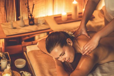 Beyaz kadın müşteri stres önleyici spa masajının keyfini çıkarıyor ve lüks otel ya da otelde sıcak mum ışığında güzellik teniyle eğleniyor. Sessiz.