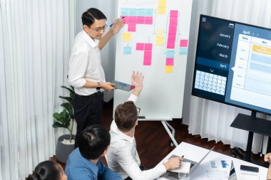 Proje yöneticisi monitörde proje yönetimi yazılım görüntülemesi, proje görevinin ilerlemesini izlemek ve toplantı masasında program planı yapmak suretiyle ekiple iletişim kurar ve işbirliği yapar. Tedbirli