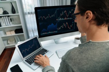 Bilgisayar ve dizüstü bilgisayarı kullanarak, çalışma masasındaki dinamik artırılmış borsa grafiğinin en yüksek kar değerini araştıran bir tüccar, modern ofisteki ekrandaki döviz kuru değerini analiz ediyor. Bireysel.