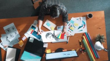 Akıllı iş adamının logo grafiği tasarlarken renk paletleri seçmesinin üst görünümü. Profesyonel iç mimar tasarımının hava görünümü ve renk paletleri kullanarak renk temasını seçin. Sempozyum.