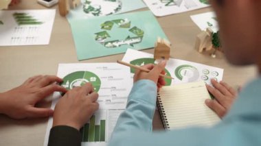 Mükemmel iş adamları, yeşil enerji grafiği kullanımı olan karmaşık bir masada eko ev projesini tartışıyor alternatif enerjiyi seçiyor ya da analiz ediyor, karbonu azaltıp dünyayı kurtarıyor. Eline odaklan. Tanımlama.