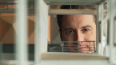 Kafkasyalı mimar mühendisinin yakın çekimi ev inşaatını denetlemek ve bina malzemelerini kontrol etmek. Proje yöneticisi modele dikkatlice bakarken kalemi işaret ediyor. Yönlendirici.